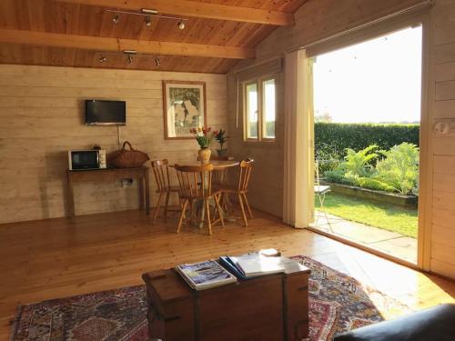 a living room with a table and a television at Tranquil Log Cabin - Beautiful Rural Sunset Views in Weston Longville
