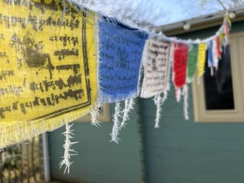 a row of prayer flags hanging in front of a house at Tranquil Norfolk Log Cabin - Stunning Rural Sunset Views in Weston Longville