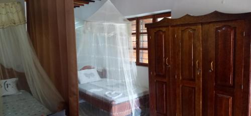 Villa Sunshine House ZANZIBAR في جامبياني: غرفة نوم مع سرير وخزانة مع شبك