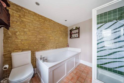 a bathroom with a white tub and a toilet at Fox Cottage, within 5 min walk of Bicester Village in Bicester