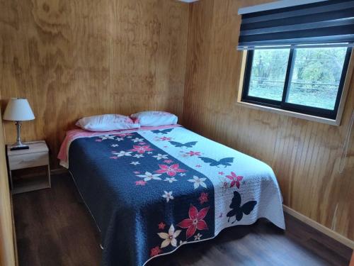 1 dormitorio con 1 cama con edredón azul y ventana en Departamento equipado Luisa en Valdivia
