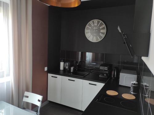 eine schwarz-weiße Küche mit einer Uhr an der Wand in der Unterkunft Heliosa Apart Gdańsk Kowale in Danzig