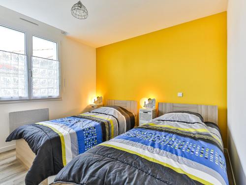 twee bedden in een kamer met gele muren bij Maison Ker Mona in Notre-Dame-de-Monts