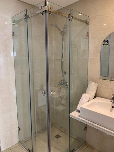 a glass shower in a bathroom with a sink at Appart hôtel Lyna el Mouradia in El Mouradia