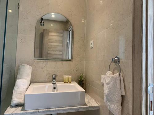 y baño con lavabo blanco y espejo. en Appart hôtel Lyna el Mouradia, en El Mouradia