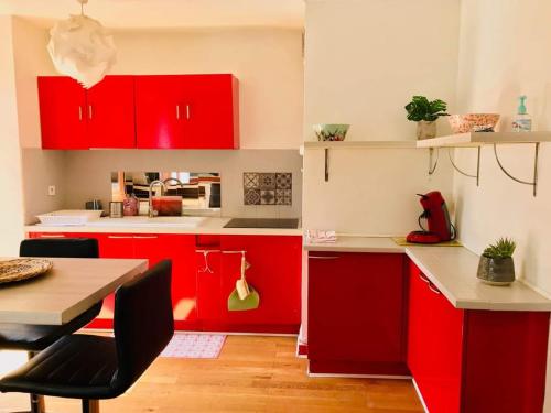 a red kitchen with red cabinets and a table at Appart hôtel Lyna el Mouradia in El Mouradia