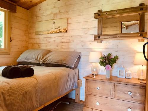 a bedroom with a bed and a wooden wall at Tranquil Log Cabin - Beautiful Rural Sunset Views in Weston Longville