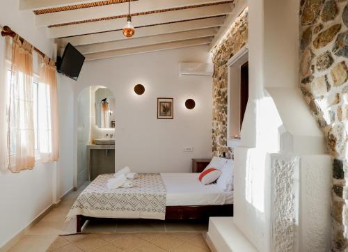 a bedroom with a bed and a stone wall at Tramonto Villa in Lagoúdi Zía