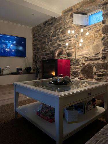 een woonkamer met een stenen muur en een tafel bij Casa con piscina in Cedeira