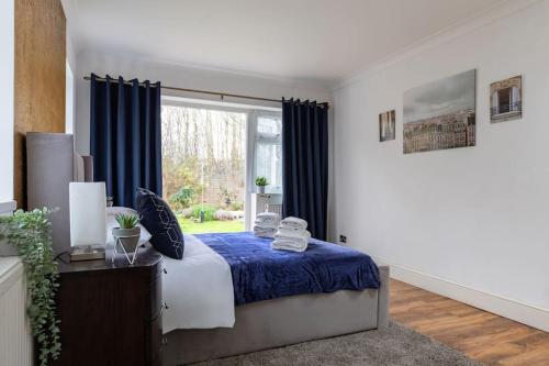a bedroom with a bed with blue sheets and a window at Relaxing Park Side Bungalow in Romford