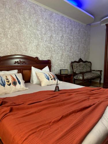 a bedroom with a large bed with an orange blanket at Guesthouse TEA in Kutaisi