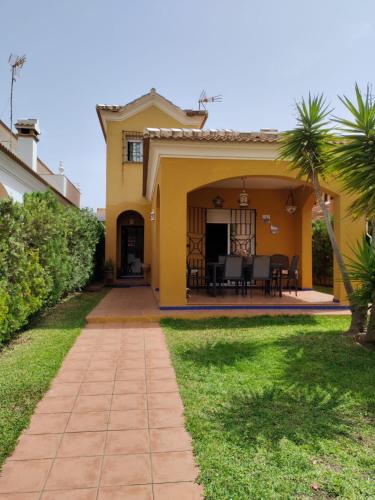 a yellow house with a patio and a yard at Matalascañas in Matalascañas