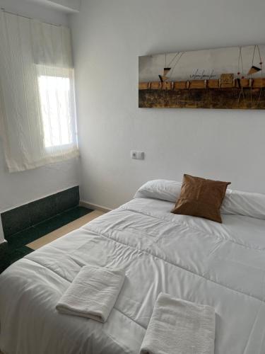 a white bed in a room with two towels on it at El Torreón 2 in Lora del Río
