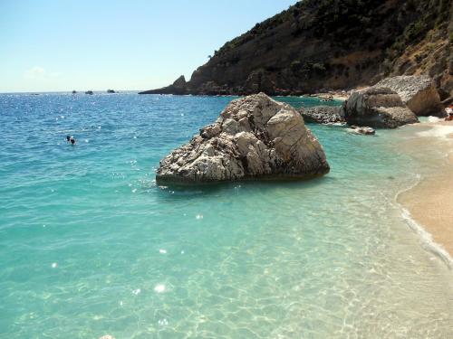 a large rock in the water next to a beach at Marina's apartment Ogliastra in Lotzorai