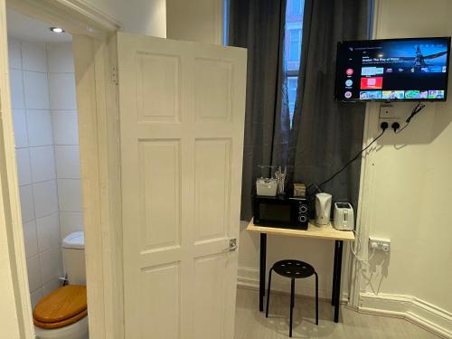 a bathroom with a toilet and a television on a door at Y2 guest house in London