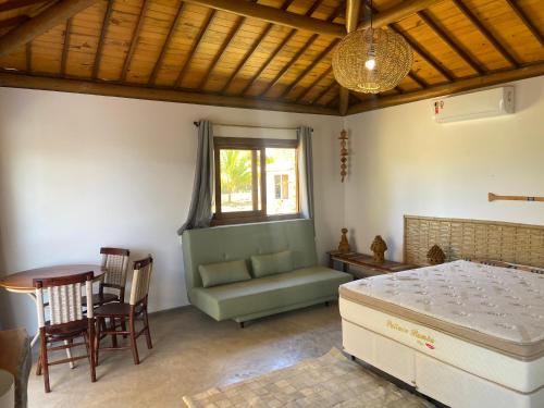 een slaapkamer met een bed, een tafel en stoelen bij Ville Santorinni in Japaratinga