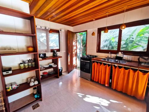 a kitchen with a sink and a counter with orange curtains at Casa Iluminalia in Abraão