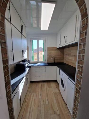 cocina con armarios blancos, lavadora y secadora en Appartement 2 chambres, rénové, climatisé, en Amélie-les-Bains-Palalda
