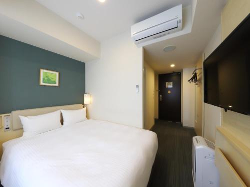 1 dormitorio con 1 cama blanca y TV en Smile Hotel Shinagawasengakujiekimae, en Tokio