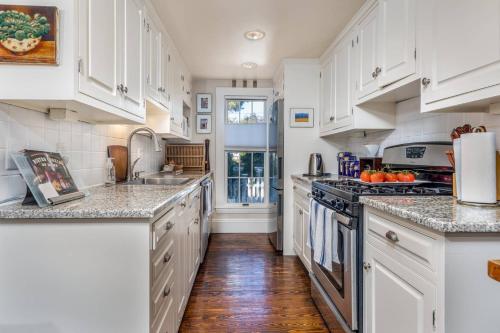 a kitchen with white cabinets and marble counter tops at SeaCity View in Swampscott