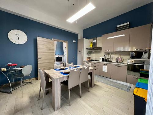 une cuisine avec une table et des chaises et une horloge au mur dans l'établissement Casa Vacanze Marina di Ragusa Il Gufo e La Civetta apt, à Marina di Ragusa