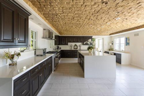 uma grande cozinha com armários pretos e um balcão branco em Bel Air Luxury Villa em Los Angeles
