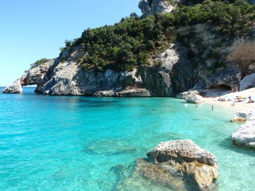 a beach with people swimming in the water at Marina's apartment Ogliastra in Lotzorai