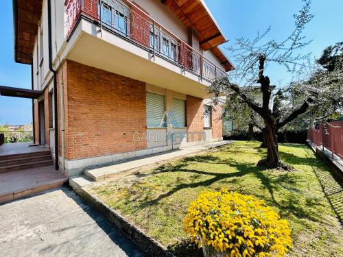 a house with a tree and yellow flowers in the yard at Ares Apartment - Vicino al Lago di Garda e alla Stazione Treno in Desenzano del Garda