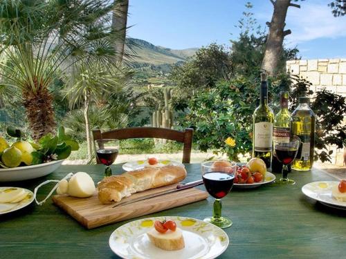 una mesa con platos de comida y botellas de vino en Scopello sul mare 2, en Castellammare del Golfo