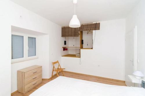 Babino PoljeにあるMljet, old stone apartment with pool in natureの白い壁のベッドルーム1室、ベッド1台、椅子1脚が備わります。