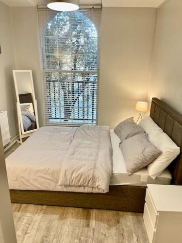 Schlafzimmer mit einem großen Bett und einem Fenster in der Unterkunft 1 bed apartment in Zone 2, minutes from Oval tube. in London