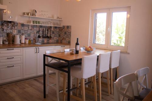 a kitchen with a table with white chairs and a window at Casa Boa Onda in Sagres