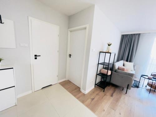 a white living room with a chair and a window at Golden Tobaco by Aparo - Winda, Łóżeczko, Balkon, Atlas Arena, ZOO, Aquapark, Piotrkowska, Park, Dworzec PKP, Ekspres do Kawy in Łódź