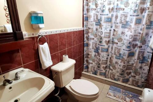 a bathroom with a toilet and a sink and a shower curtain at Huellas en la arena Casa De Playa in Tela