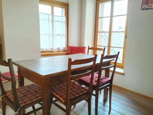 einen Esstisch und Stühle in einem Zimmer mit Fenstern in der Unterkunft L'Abete Bianco Casa in montagna in Vezzano