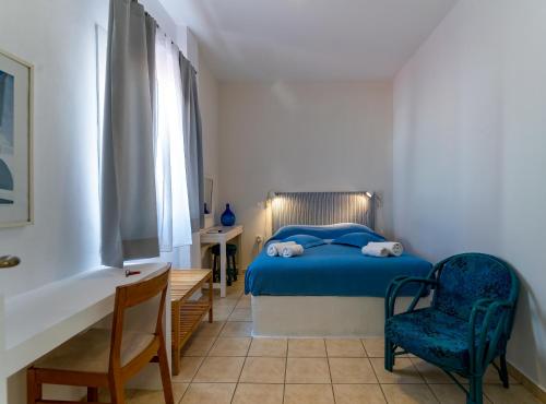 a bedroom with a blue bed and a table and chairs at Manto Hotel in Mikonos