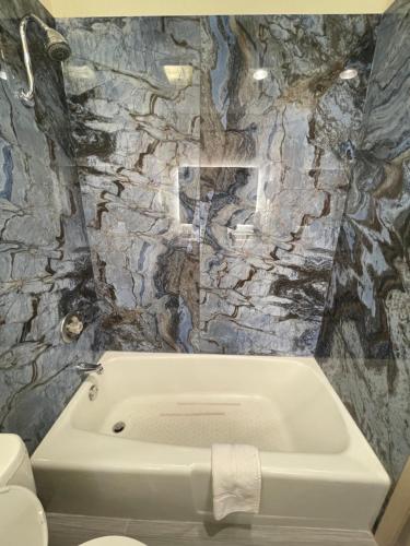 ein Badezimmer mit einer Badewanne in einer Steinwand in der Unterkunft Super 8 by Wyndham Wooster in Wooster