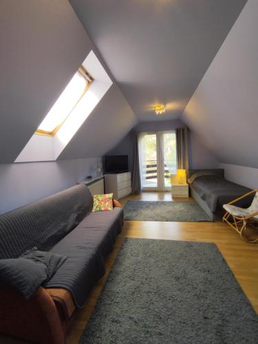 a attic living room with a couch and a window at Dom na Zaciszu in Warsaw