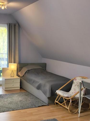 a bedroom with a bed and a chair and a window at Dom na Zaciszu in Warsaw