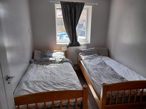 Bethel- beautiful new 1 bed house near Erith station في Erith: سريرين في غرفة صغيرة مع نافذة
