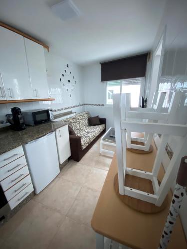 cocina y sala de estar con armarios blancos y sofá en Bueu en Bueu