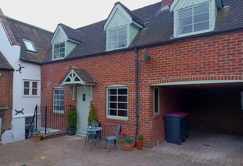 a brick house with a patio with a table and chairs at Forget Me Not Cottage in Ironbridge