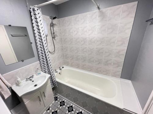 a bathroom with a white tub and a sink at Cliff Haven, Sea View Holiday Home. in Cullercoats