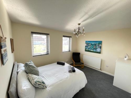 Un dormitorio con una gran cama blanca y una silla. en Cliff Haven, Sea View Holiday Home., en Cullercoats