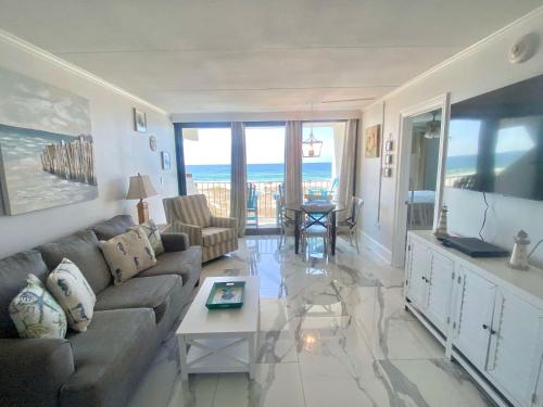 a living room with a couch and a flat screen tv at Island Winds East 202 by ALBVR - Beautifully renovated beachfront condo & steps away from Hangout & more! in Gulf Shores