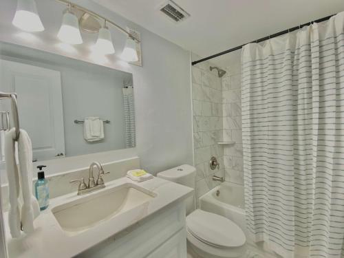 Baño blanco con lavabo y aseo en Island Winds East 202 by ALBVR - Beautifully renovated beachfront condo & steps away from Hangout & more!, en Gulf Shores