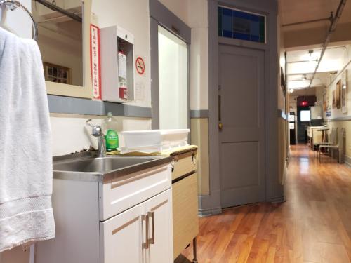 a kitchen with a sink and a hallway at St. Clair Hotel Hostel in Vancouver