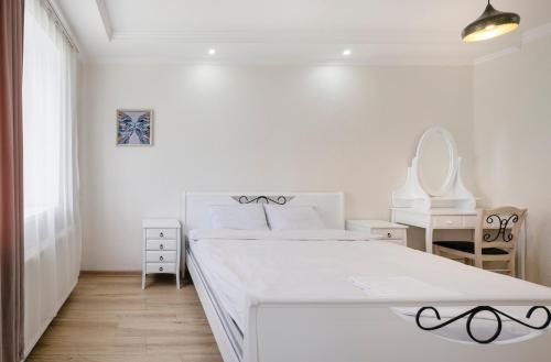 een witte slaapkamer met een bed en een spiegel bij Marcos Hotel in Nizhnyaya Alekseyevka