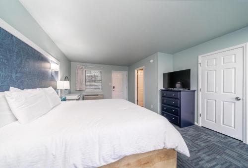 a bedroom with a large white bed and a television at The Hamilton - Lakefront & Studio Suites, Hot Springs in Hot Springs