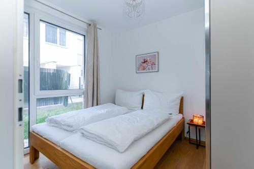 uma cama num quarto com uma grande janela em Modern apartment with tiny garden near city center em Viena